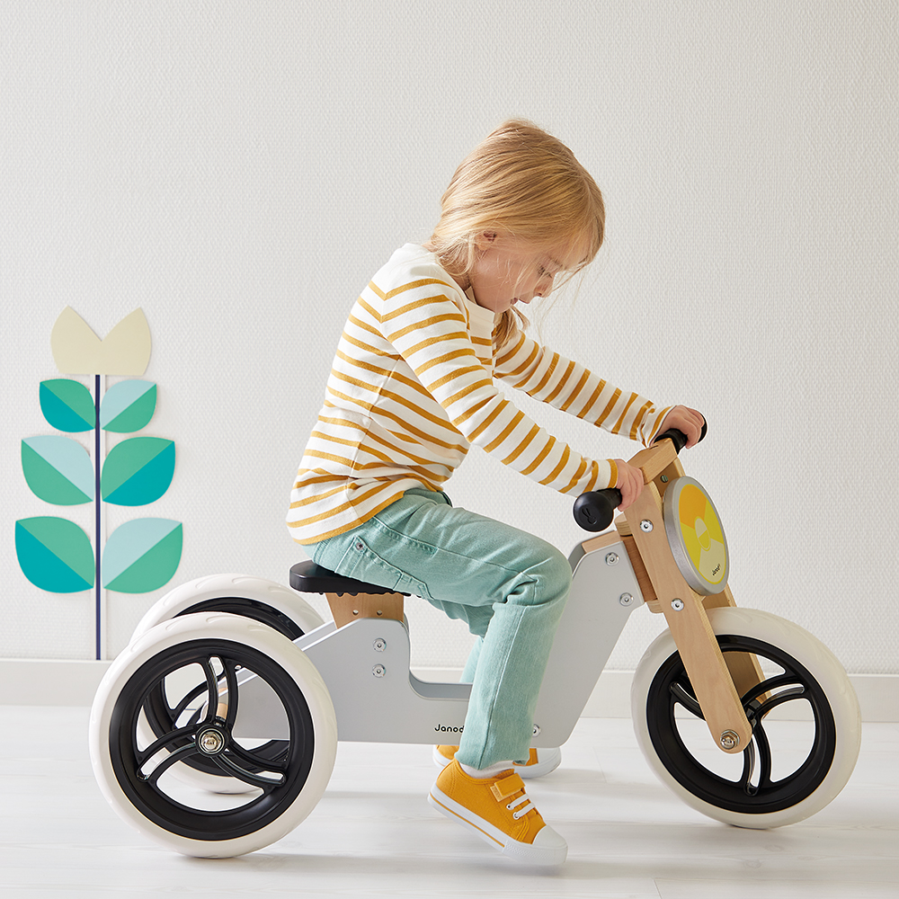 Enfant jouant avec une draisienne en bois Janod