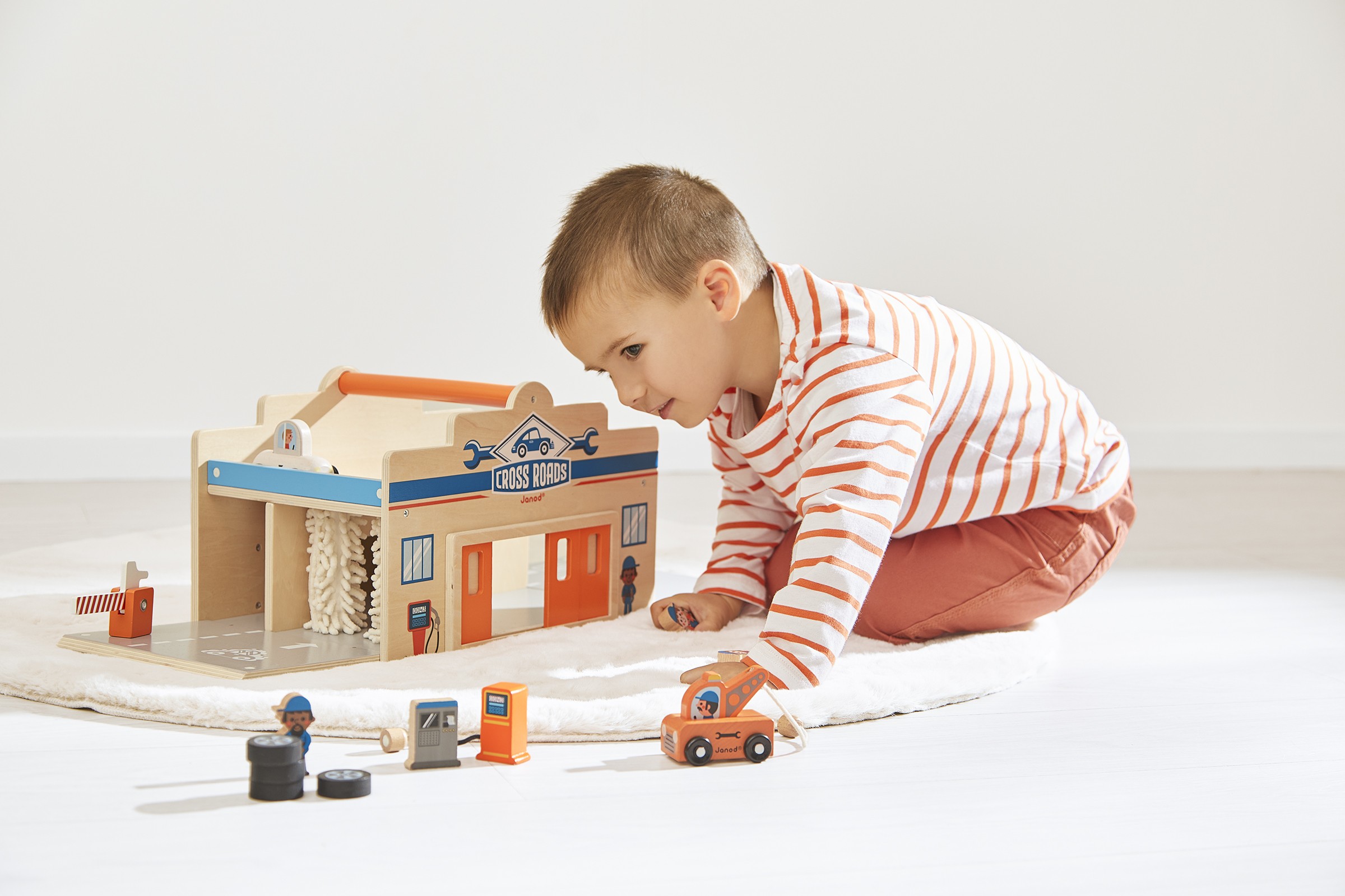 Enfant jouant avec le Garage en bois Ville Cross Roads de JANOD