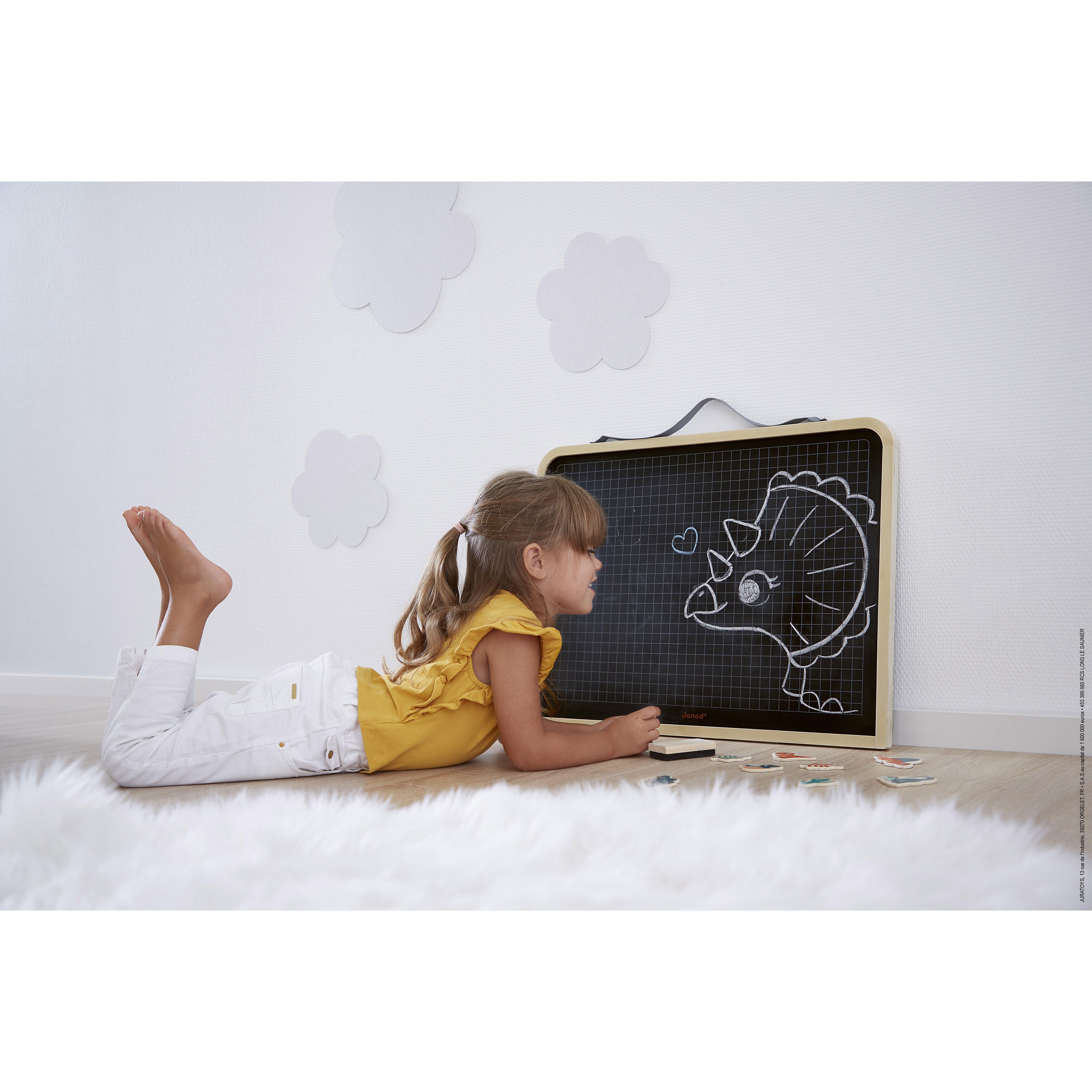 Enfant dessinant sur un tableau en bois Janod
